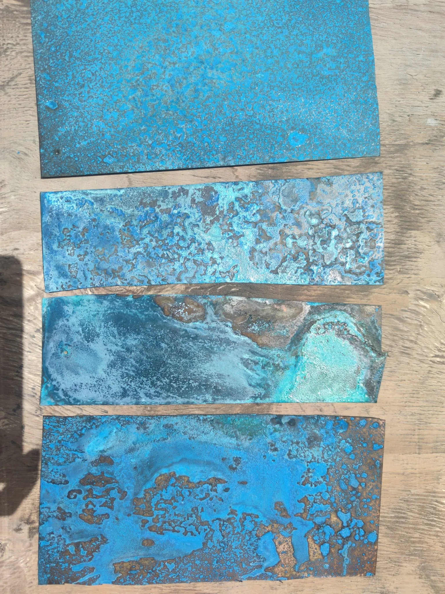 copper panels patinated in blues and greens, laid out in a row