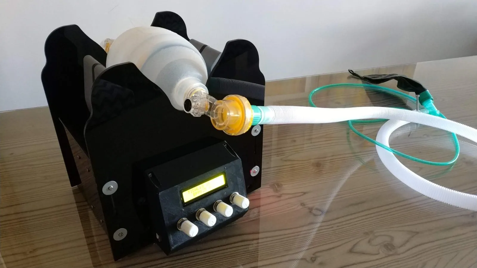 the e-vent mlt ventilator: a black housing with a display and dials, an ambu-bag held in its jaw