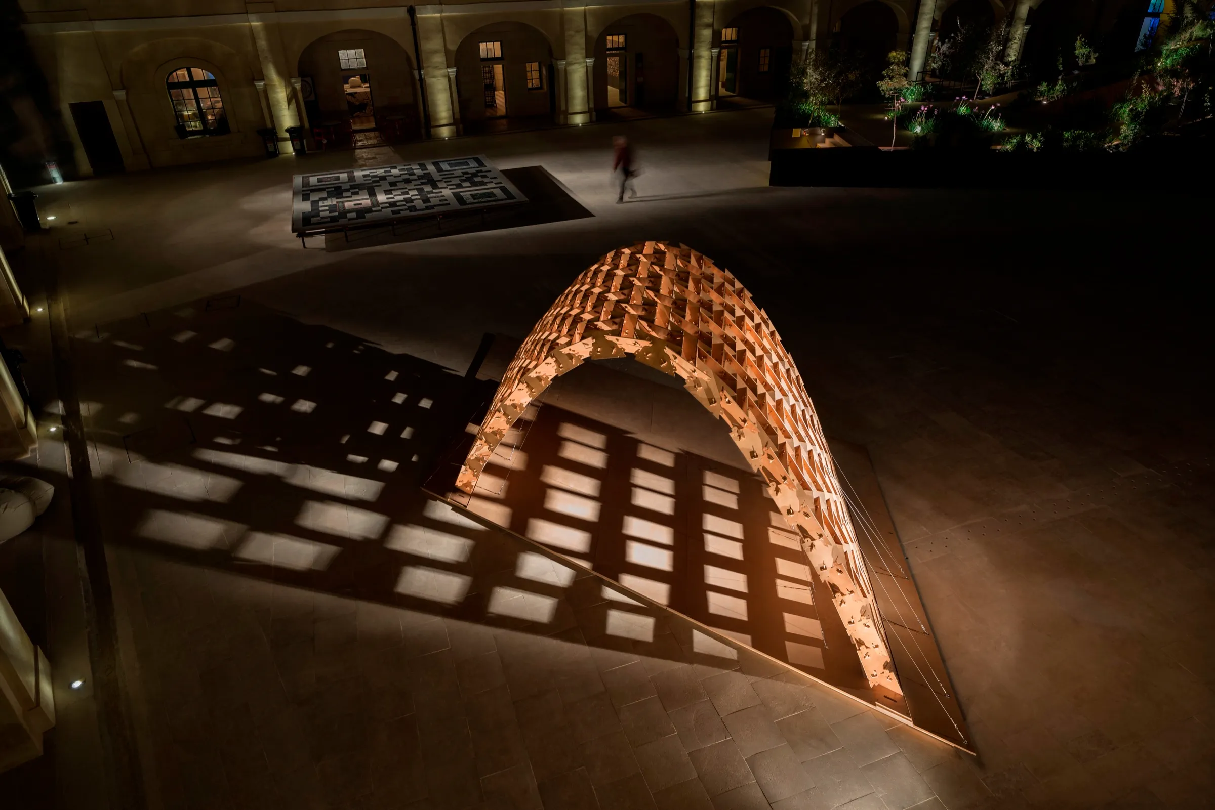 The MDW 2014 pavilion at night in the courtyard of Fort St Elmo, its plywood vault casting a grid of light across the floor