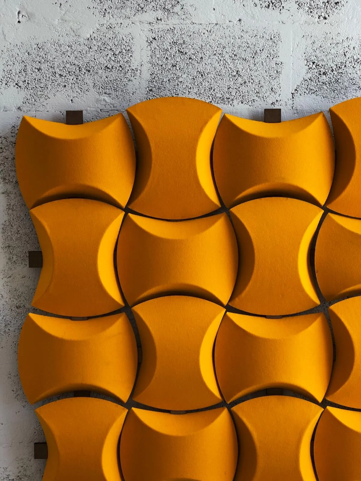 curved orange tiles fixed in a repeating pattern on a block wall