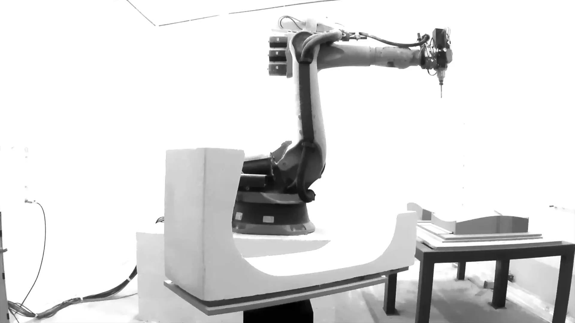 The robot arm milling a curved seat form out of a white foam block