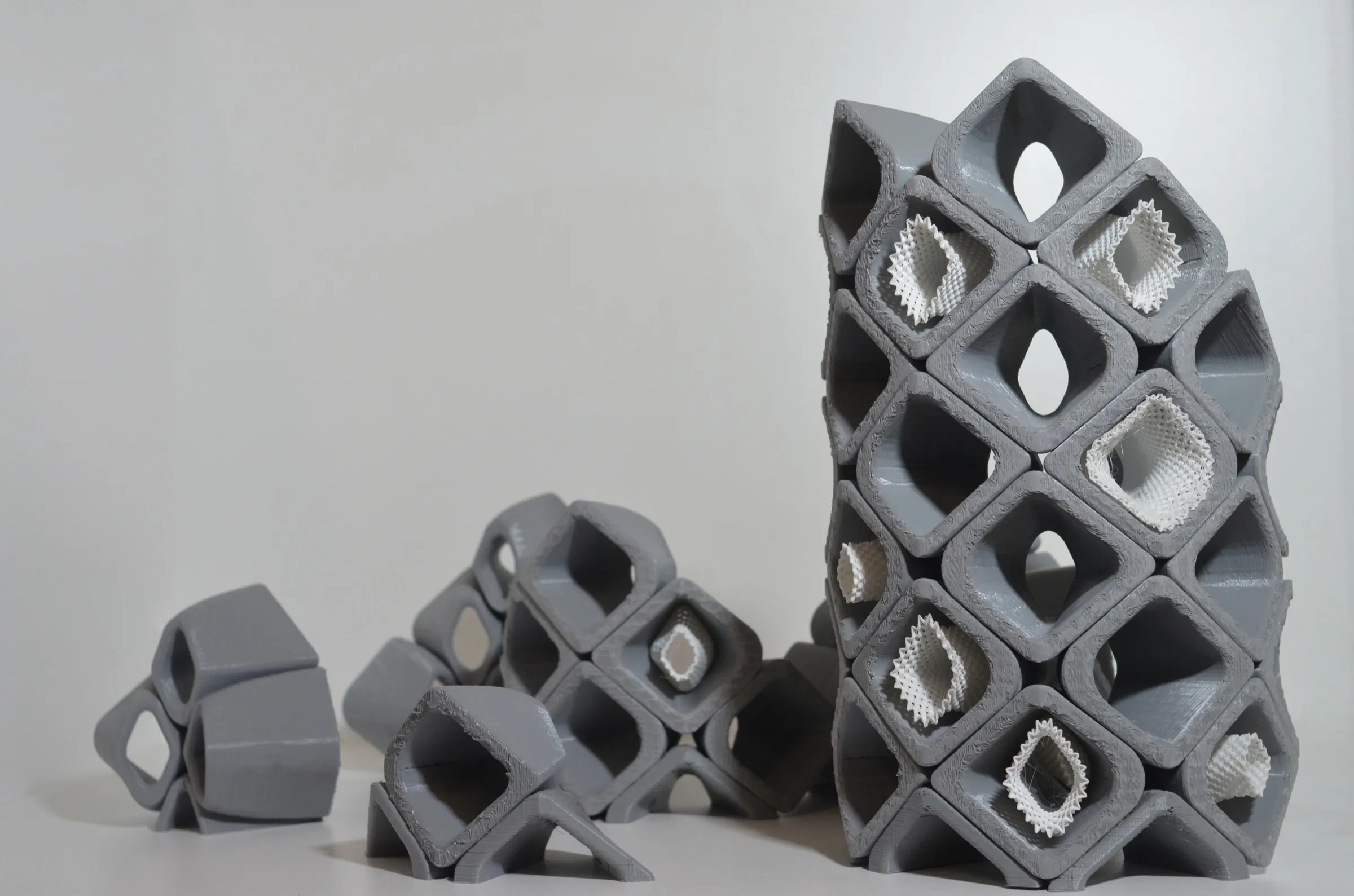 A 1:3 model of the Sikka diagrid: grey cells stacked into a tower, some holding white ribbed inserts, all printed in plastic